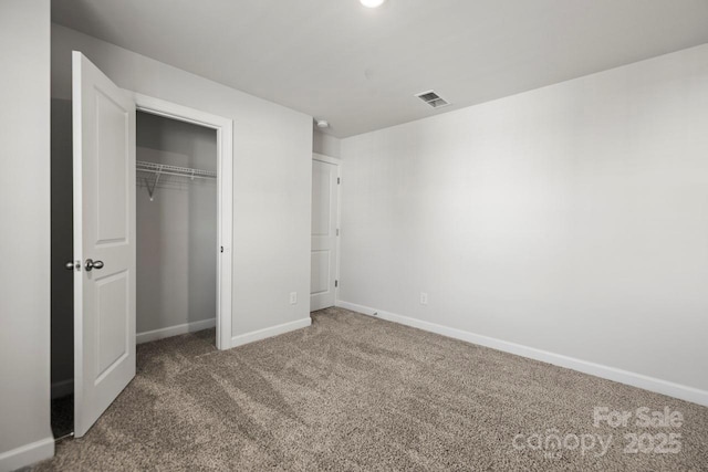 unfurnished bedroom featuring carpet floors, baseboards, visible vents, and a closet