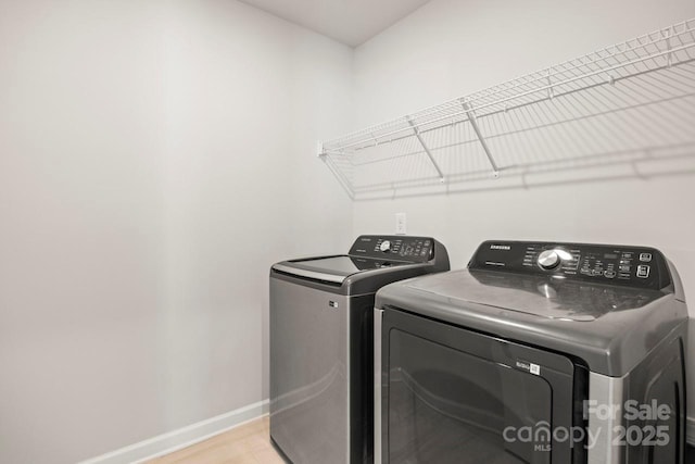 laundry room with laundry area, washer and clothes dryer, light wood-style flooring, and baseboards