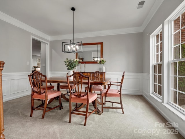 dining space with ornamental molding, wainscoting, and light carpet