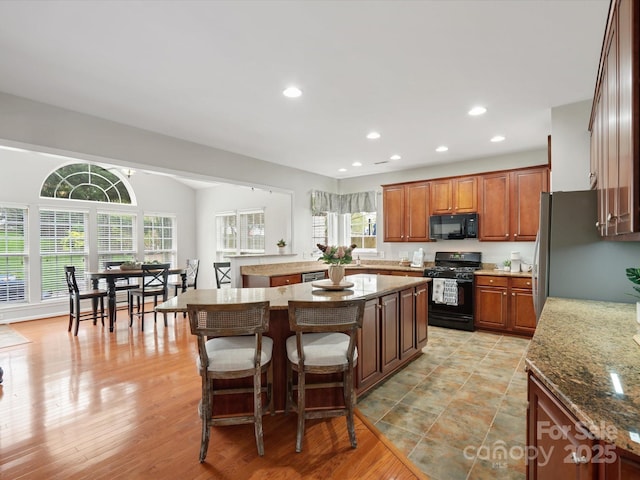 kitchen featuring a kitchen island, recessed lighting, a healthy amount of sunlight, and black appliances