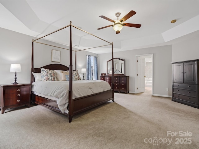 bedroom with a ceiling fan, baseboards, light carpet, and ensuite bath