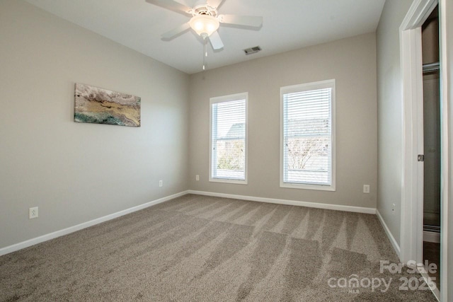 empty room with a ceiling fan, carpet, visible vents, and baseboards