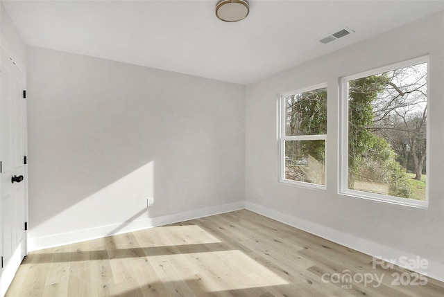 spare room featuring baseboards, visible vents, and light wood finished floors