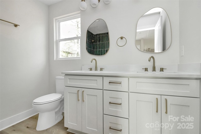 full bathroom with double vanity, toilet, baseboards, and a sink