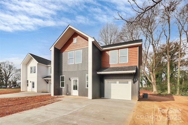 view of front of property featuring a garage, central AC unit, and driveway