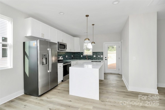 kitchen with light wood-style flooring, light countertops, white cabinets, appliances with stainless steel finishes, and tasteful backsplash