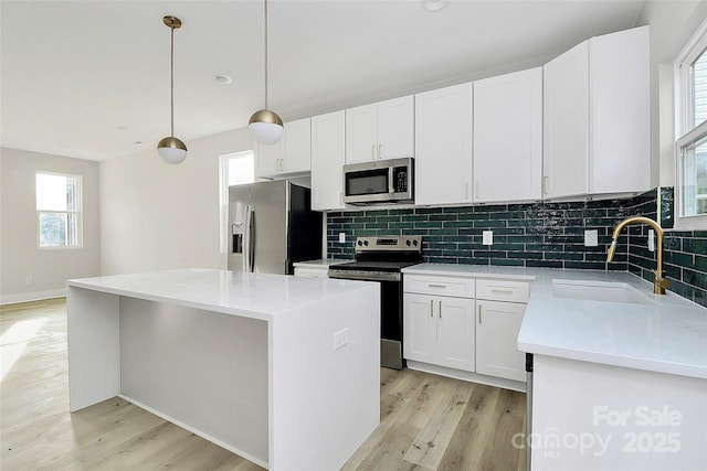 kitchen featuring a sink, backsplash, appliances with stainless steel finishes, and light wood-style flooring