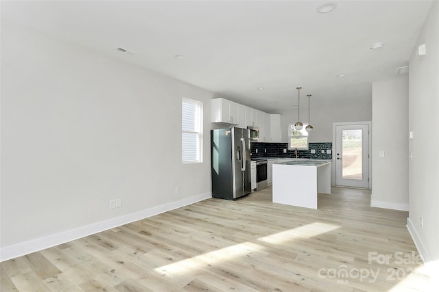 kitchen featuring light wood-style flooring, a kitchen island, tasteful backsplash, white cabinetry, and stainless steel appliances