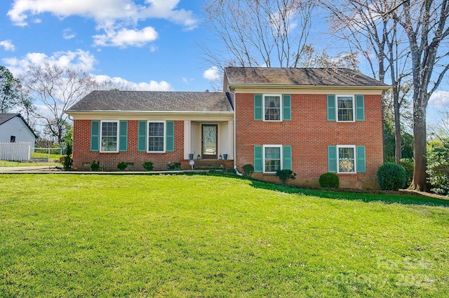 split level home with brick siding, a front yard, and fence