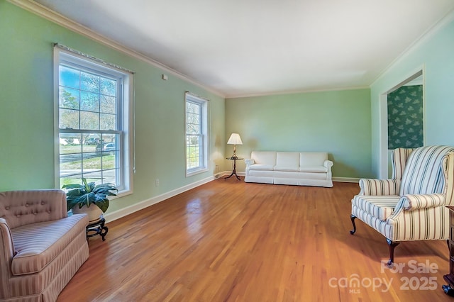 living area with crown molding, baseboards, and wood finished floors