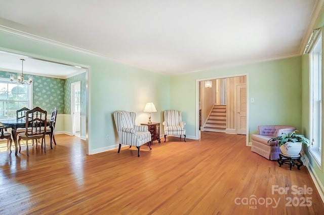 living area with wallpapered walls, stairs, an inviting chandelier, and wood finished floors