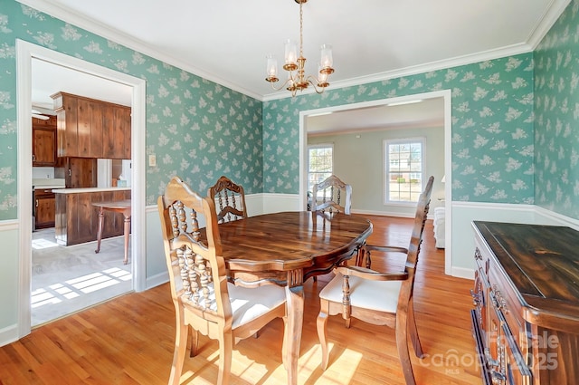 dining space with wallpapered walls, an inviting chandelier, crown molding, and light wood-type flooring