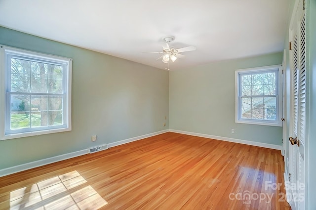 spare room featuring a wealth of natural light, visible vents, and baseboards