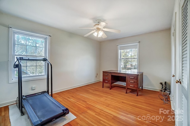 workout area featuring baseboards, light wood-style floors, and ceiling fan