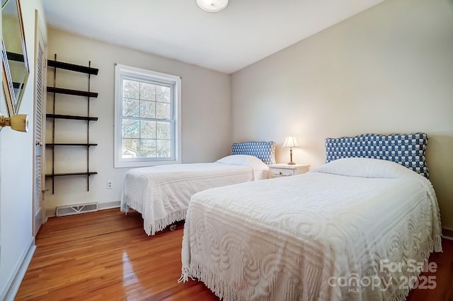 bedroom featuring wood finished floors, visible vents, and baseboards