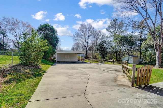 view of home's exterior featuring an attached carport, an outbuilding, fence, a yard, and concrete driveway