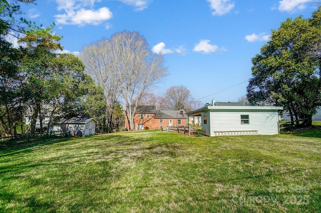 view of yard featuring a wooden deck, an outbuilding, and a shed