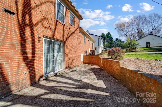 view of home's exterior featuring brick siding, central air condition unit, a patio area, and fence