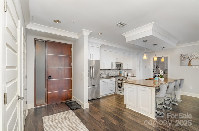 kitchen featuring dark wood-style floors, tasteful backsplash, white cabinetry, and stainless steel appliances