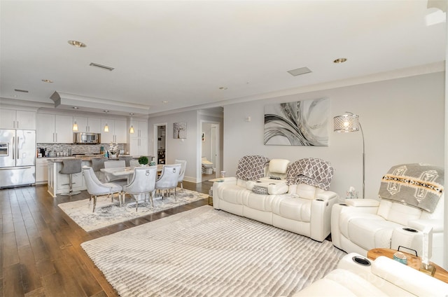 living room with dark wood-style floors, crown molding, recessed lighting, visible vents, and baseboards