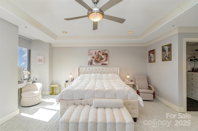 bedroom featuring a tray ceiling, ceiling fan, and baseboards