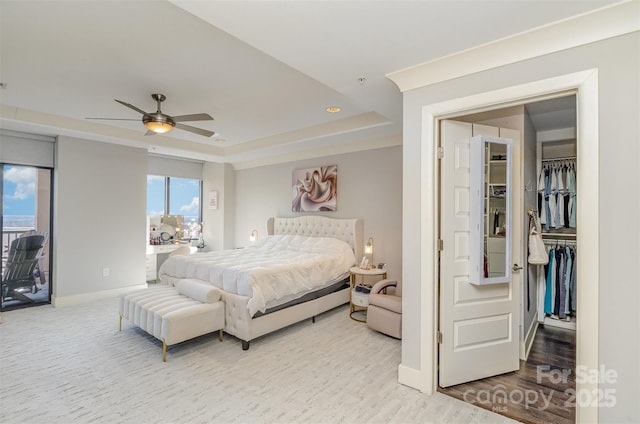 bedroom with access to outside, multiple windows, baseboards, and a raised ceiling