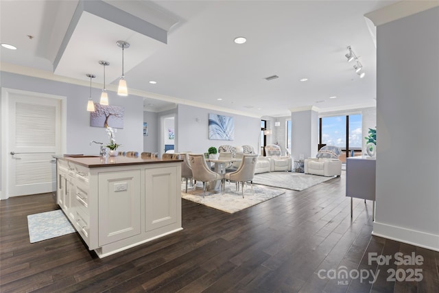 kitchen with a center island, crown molding, dark wood-type flooring, white cabinets, and a sink