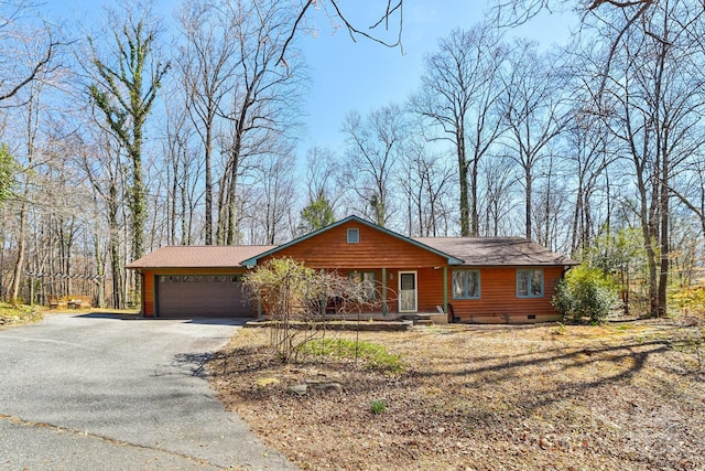 chalet / cabin featuring driveway, a porch, crawl space, and an attached garage