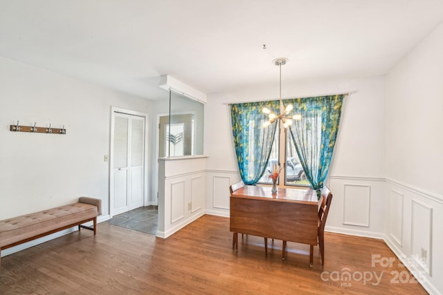 dining space featuring an inviting chandelier, wood finished floors, and wainscoting