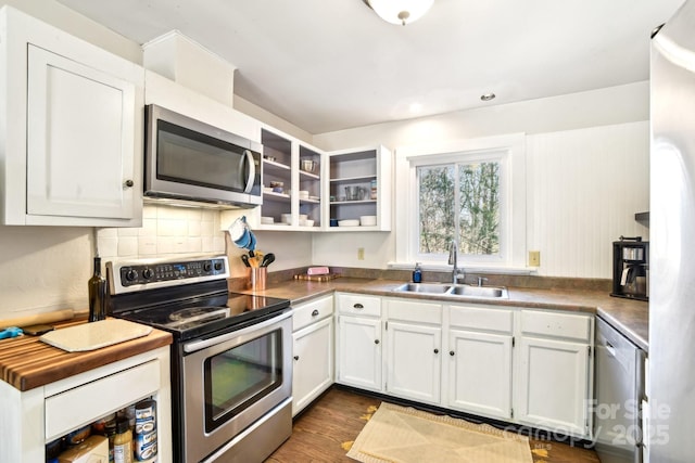 kitchen featuring white cabinets, dark wood finished floors, appliances with stainless steel finishes, a sink, and backsplash