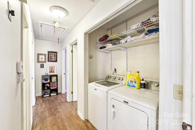 washroom with washing machine and clothes dryer, attic access, light wood-style floors, laundry area, and baseboards