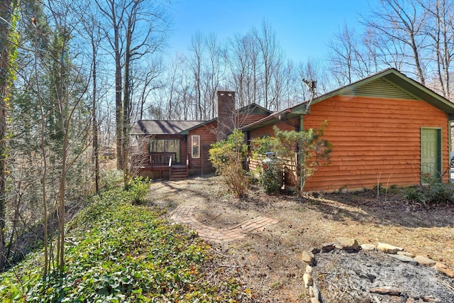 view of side of home featuring a chimney and a wooden deck