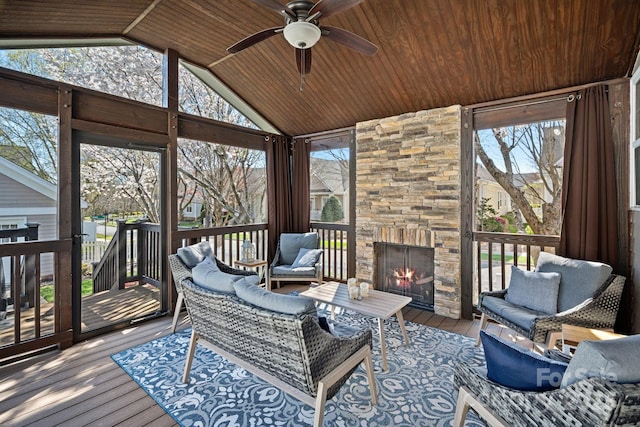 sunroom / solarium featuring a ceiling fan, wood ceiling, a fireplace, and vaulted ceiling