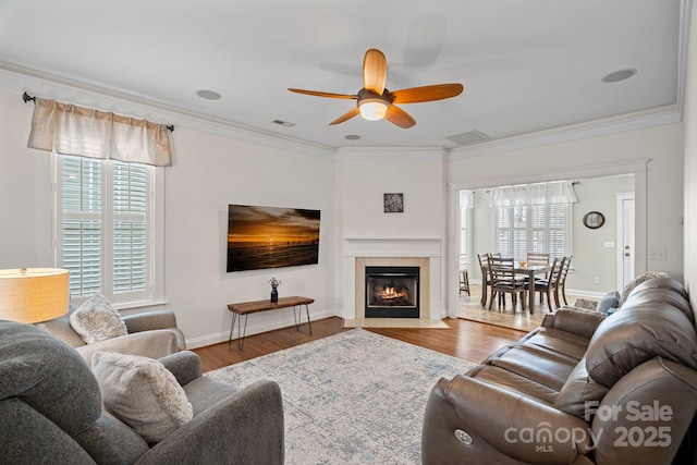 living room with visible vents, ornamental molding, ceiling fan, and wood finished floors