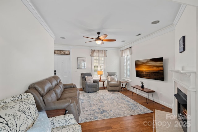 living room featuring a fireplace with flush hearth, wood finished floors, and crown molding