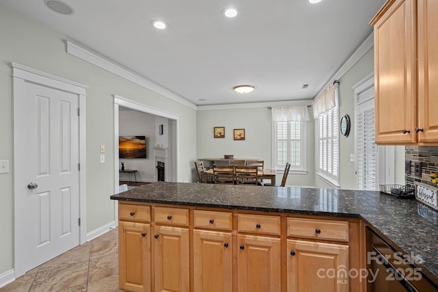 kitchen with dark stone counters, crown molding, a peninsula, and decorative backsplash