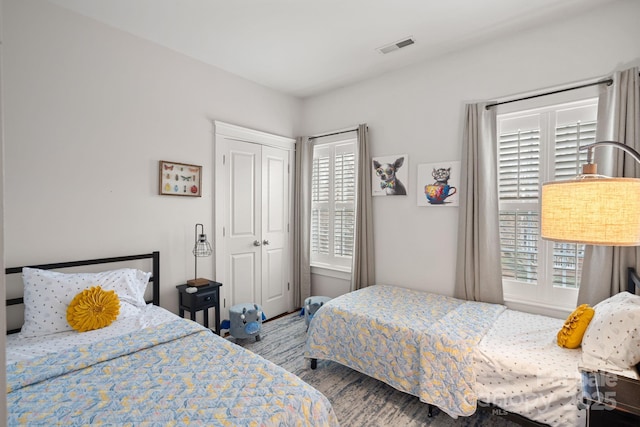 bedroom featuring visible vents, a closet, and wood finished floors