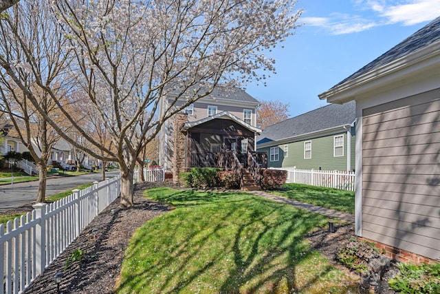 view of yard featuring a residential view, a sunroom, and a fenced backyard