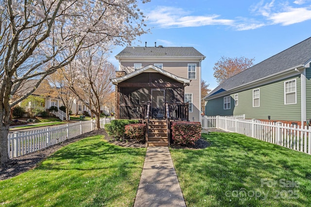 back of property with fence private yard, a sunroom, and a lawn