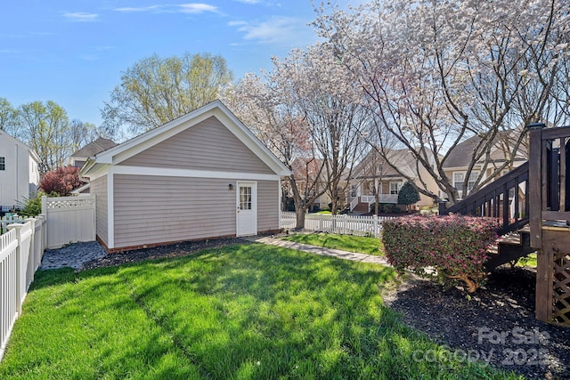 back of house with a fenced backyard, a lawn, an outdoor structure, and stairs