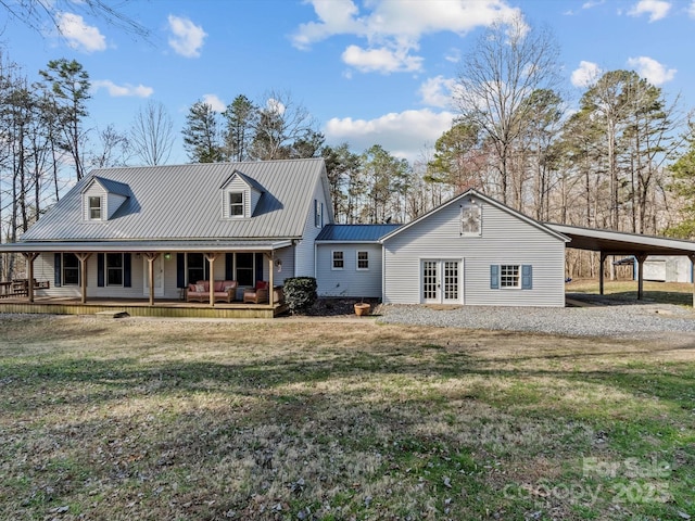 view of front of property featuring driveway, metal roof, an attached carport, french doors, and a porch