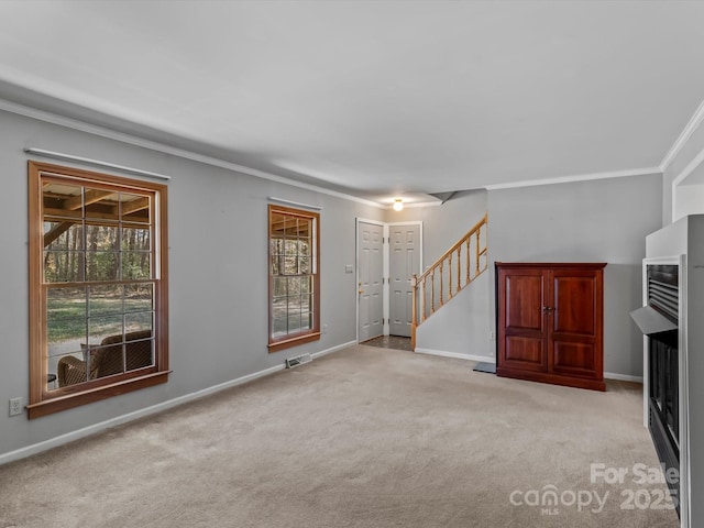 unfurnished living room featuring baseboards, visible vents, stairway, crown molding, and carpet flooring