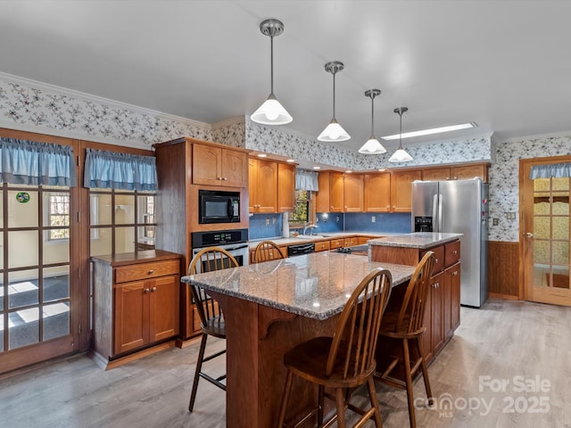 kitchen featuring a wainscoted wall, appliances with stainless steel finishes, ornamental molding, a kitchen island, and wallpapered walls