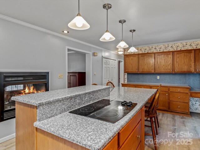 kitchen featuring brown cabinets, crown molding, light wood-style flooring, and black electric cooktop