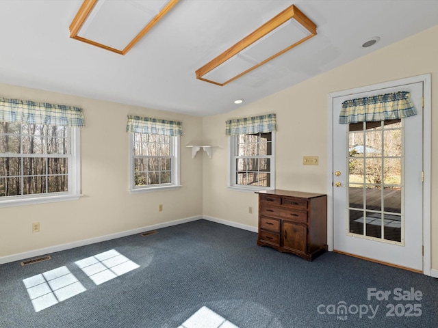 spare room featuring dark colored carpet, visible vents, vaulted ceiling, and baseboards