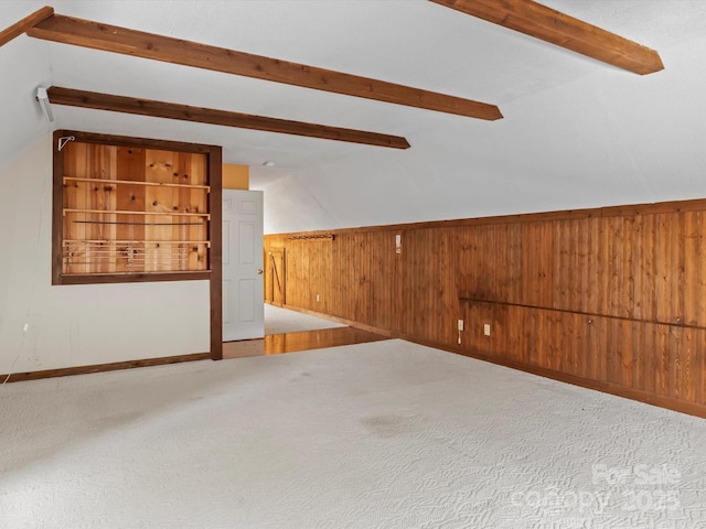 interior space featuring carpet floors, wooden walls, and lofted ceiling with beams