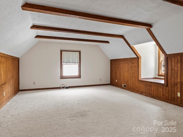 bonus room featuring carpet, vaulted ceiling with beams, visible vents, wooden walls, and a textured ceiling