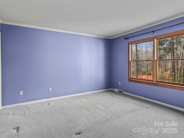 carpeted empty room featuring crown molding, visible vents, and baseboards