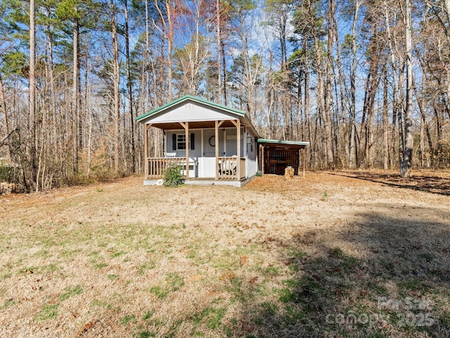 view of front of property with an outdoor structure and a wooded view