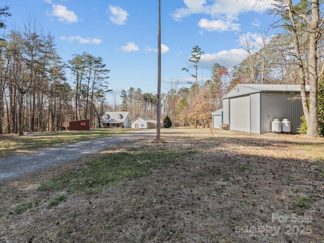 view of yard featuring a garage, driveway, and an outdoor structure